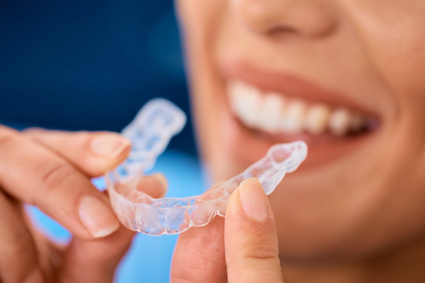 A patient holding her clear Invisalign aligner